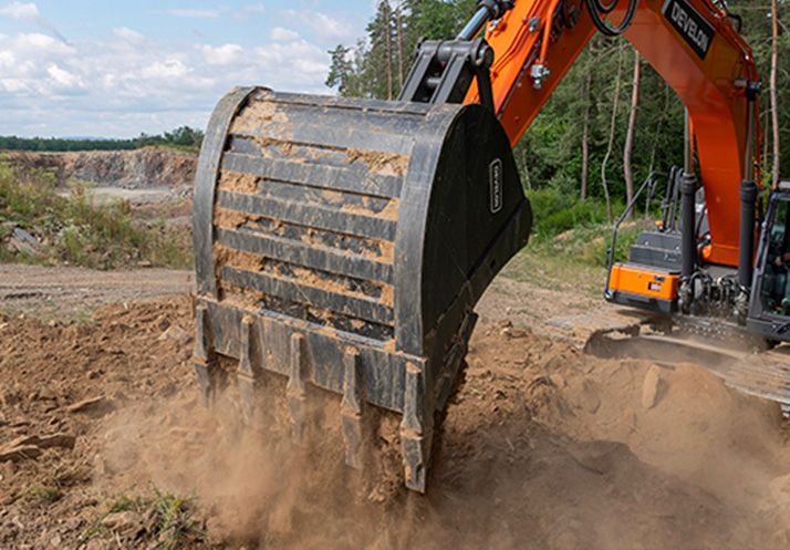 Excavation construction with Develon excavator showcasing fuel efficiency and force, digging a massive hole in a forest setting